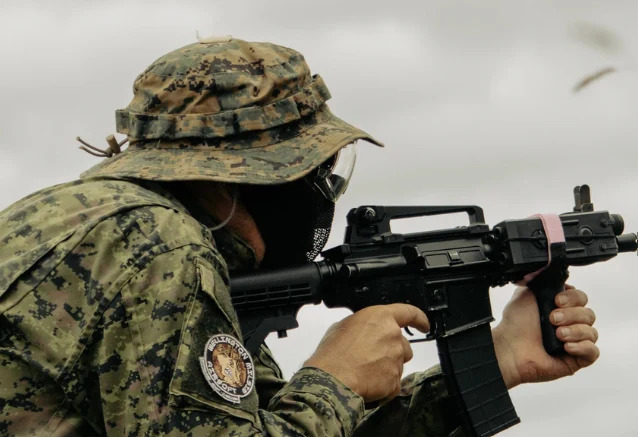 Airsoft player aiming a rifle in the field near Wellington